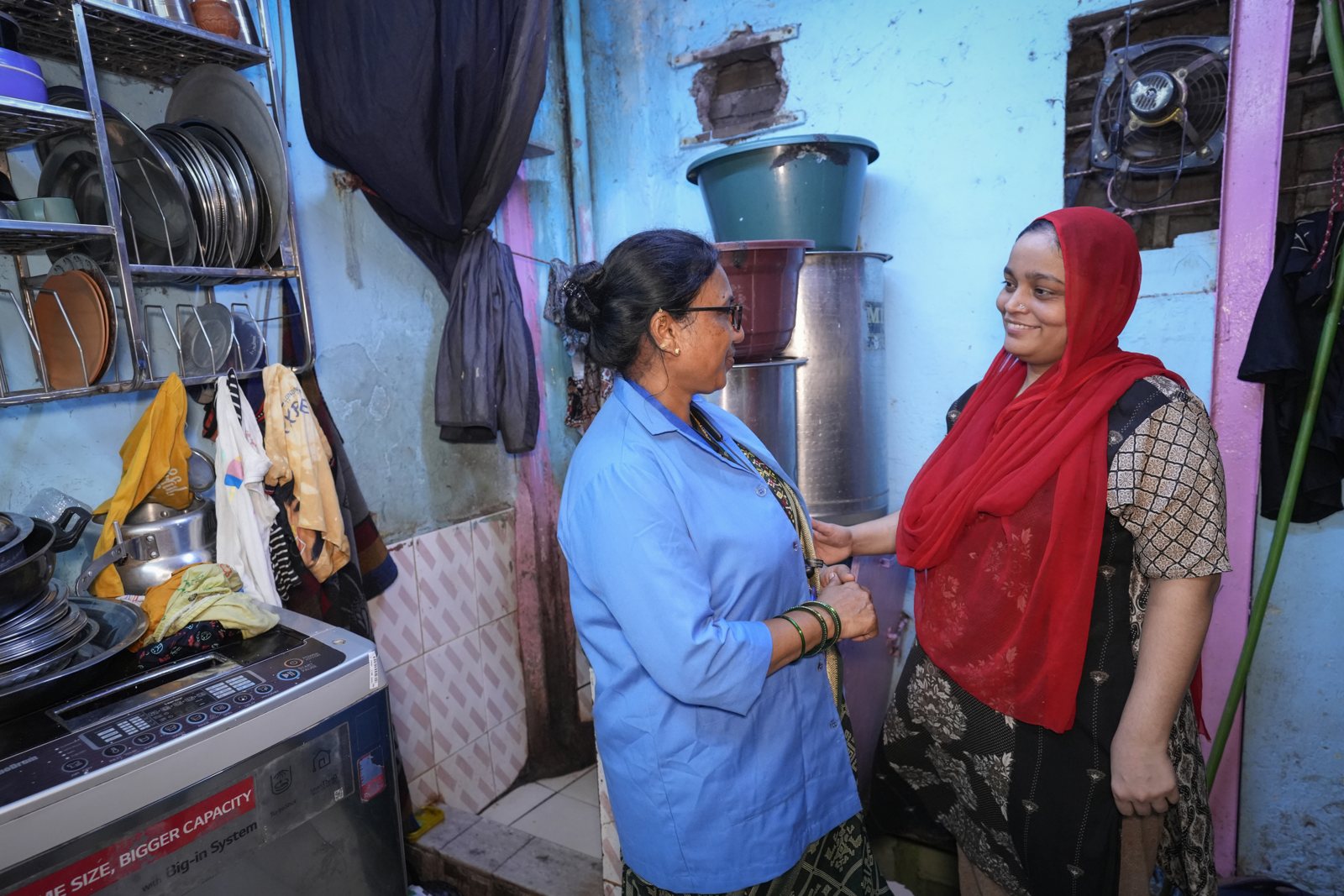 Heena Imran Khan, in a red dupatta, talking with a member of the hub team in her kitchen in Mumbai East